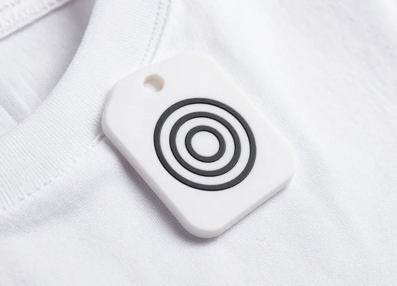 A close-up shot of a modern RFID tag attached to a high-quality fabric garment on a clean white background.