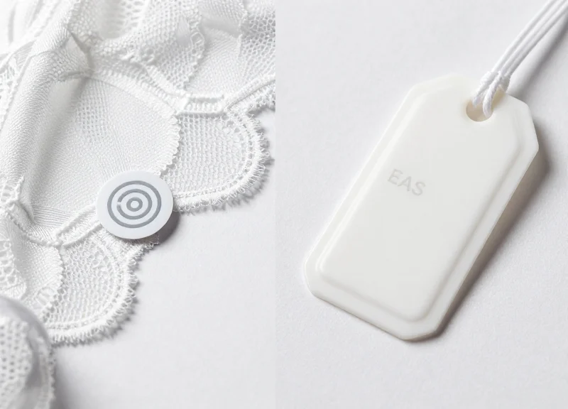 A professional side-by-side studio shot showing a small, modern discreet RFID sensor on the left and a larger traditional plastic security tag on the right, both attached to delicate lace fabric.