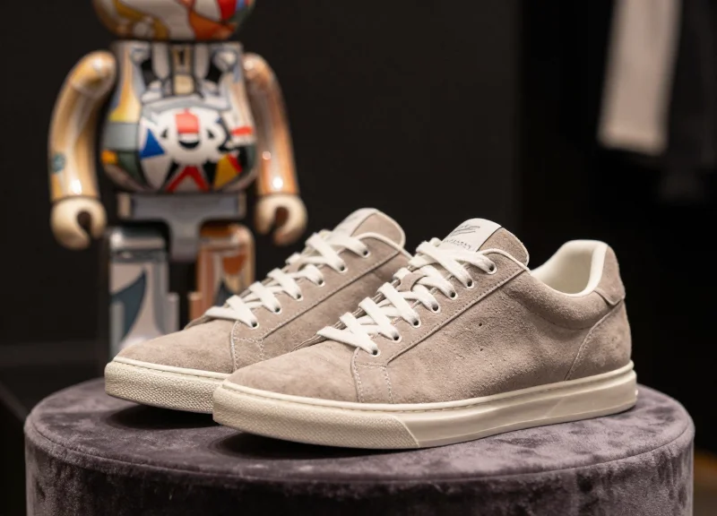 Close-up of limited edition suede sneakers and a designer vinyl toy on a premium display stand.
