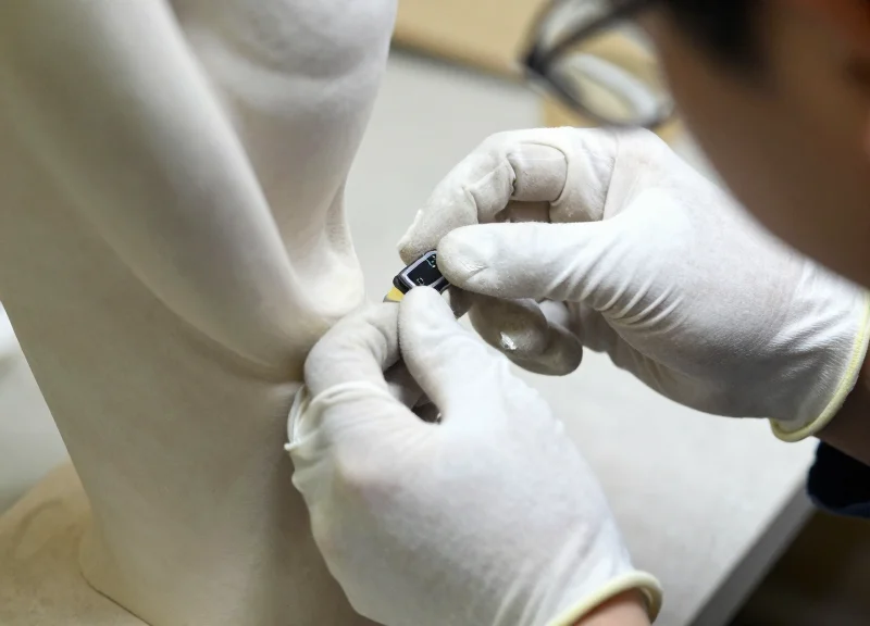 A professional conservator in white gloves applying a security tag to an artwork.