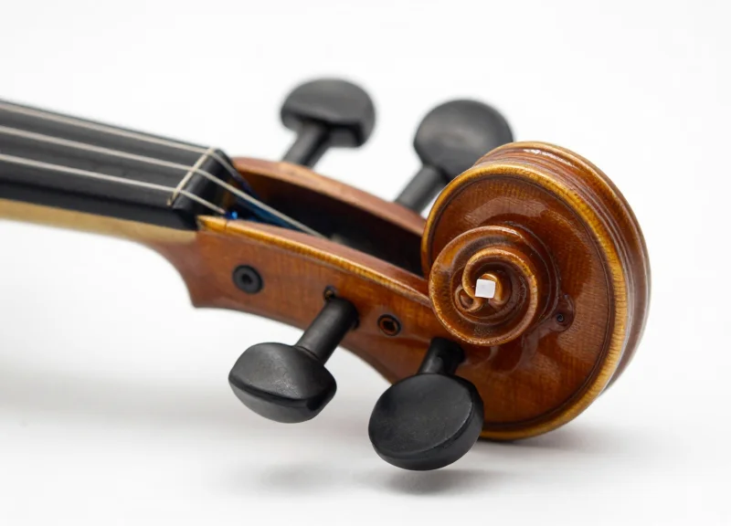 A macro close-up of a violin's wooden scroll showing a tiny, discreet, almost invisible RFID tag.