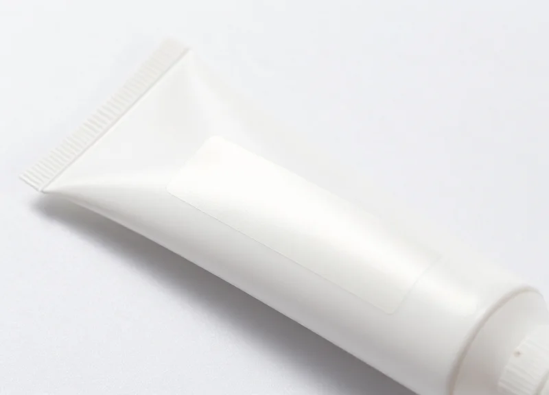 A white squeezable tube showing a flexible security label perfectly adhered to its curved surface.