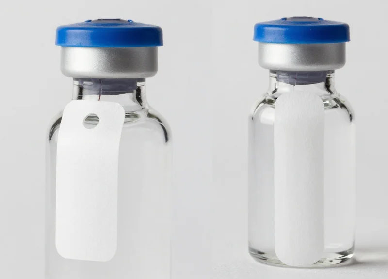 Comparison between a physical bottle neck tag and a flexible adhesive security label on premium bottles.