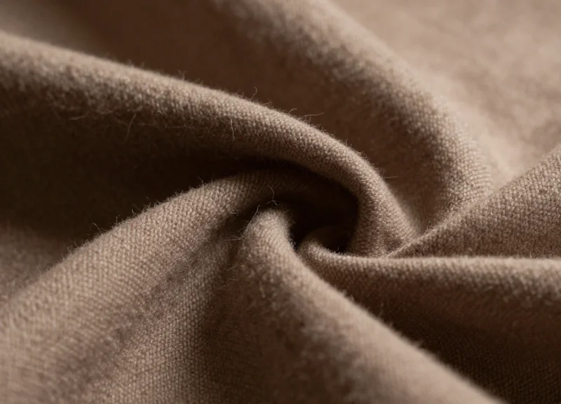 Close-up shot of high-end silk and cashmere fabric folds under warm cinematic lighting
