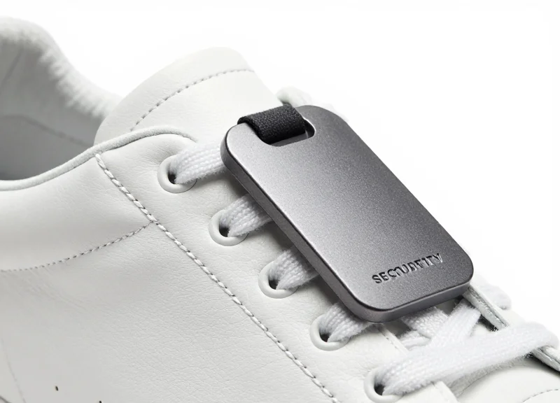 Close-up of a high-quality EAS shoe tag attached to the eyelet of a leather sneaker on a clean white background.