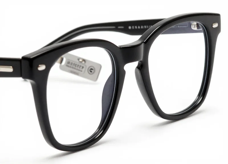 A macro shot of a pair of high-end eyeglass frames showing a small, discreet and aesthetically pleasing security tag attached to the temple.