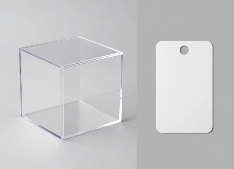 Side-by-side comparison of a physical security box and a thin electronic tracking sticker on a clean background.