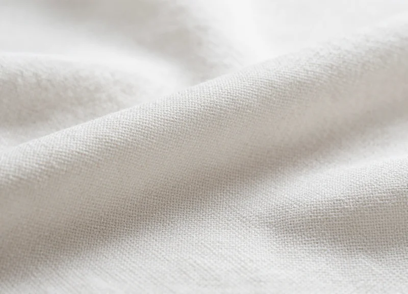 Macro photograph of the high-thread-count weave of luxury white linen.