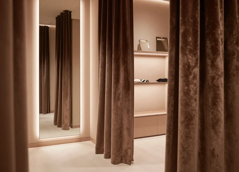 An elegant, modern fitting room area in an upscale intimate apparel boutique with soft lighting and luxurious curtains.