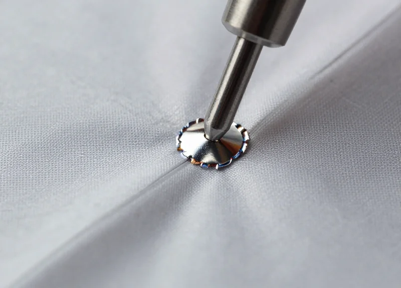 Macro photography of an industrial welding point on synthetic fabric.