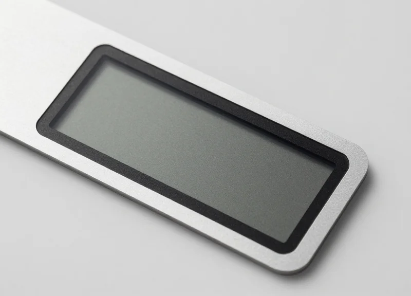 A close-up of a sleek, thin electronic ink display label with a matte paper-like screen finish on a neutral background.