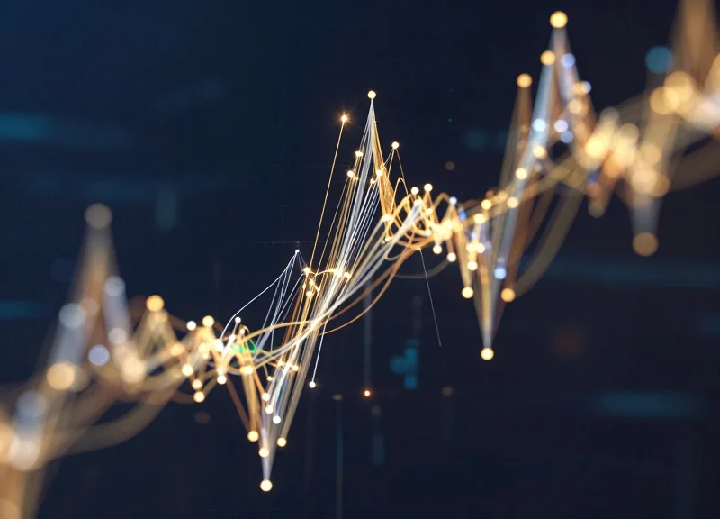 Abstract data visualization showing glowing gold and silver light trails moving in a dynamic upward curve.