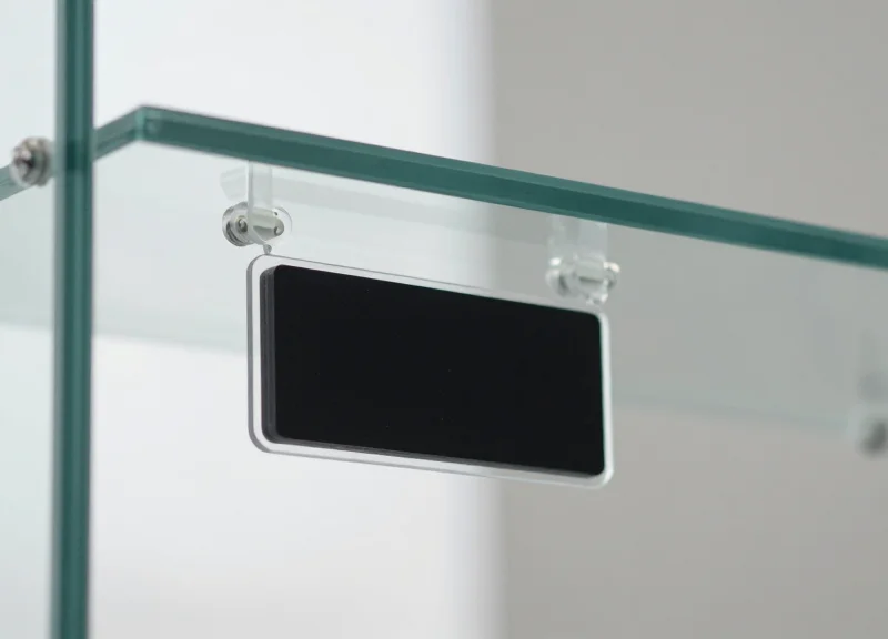 An electronic shelf label mounted seamlessly to a clean glass retail counter.