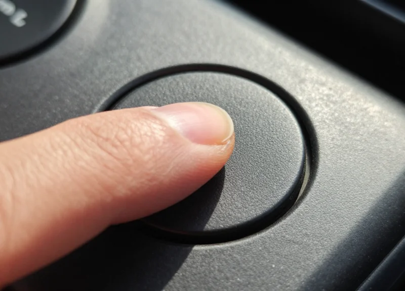 Macro close-up of a worker's finger pressing a physical mechanical button on an industrial device for haptic feedback.