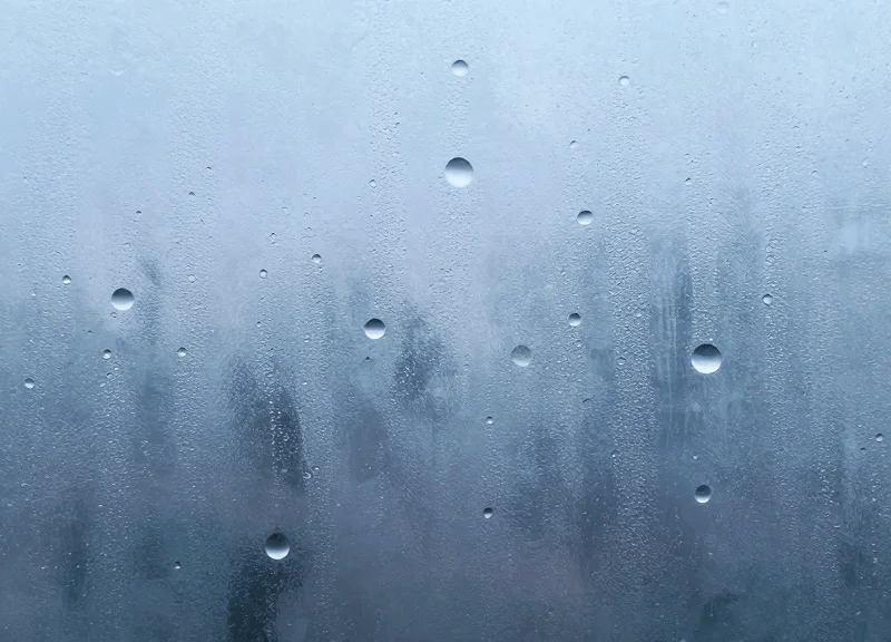 An abstract visualization of moisture particles condensing on a cold surface to represent fogging.